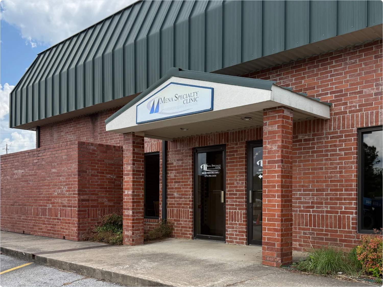 Exterior of the Mena Specialty Clinic, a brick building with a green awning.